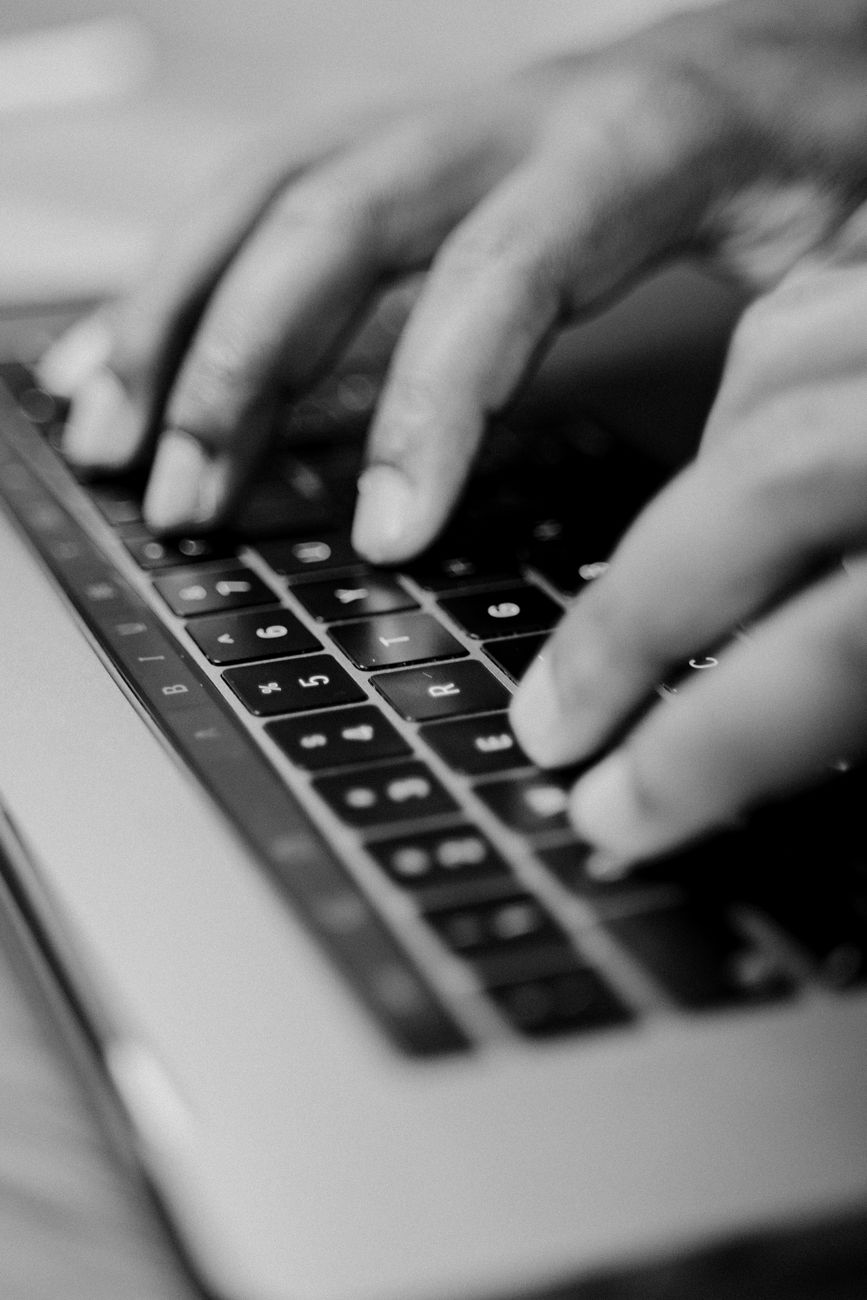 grayscale photography of hands typing on a keyboard